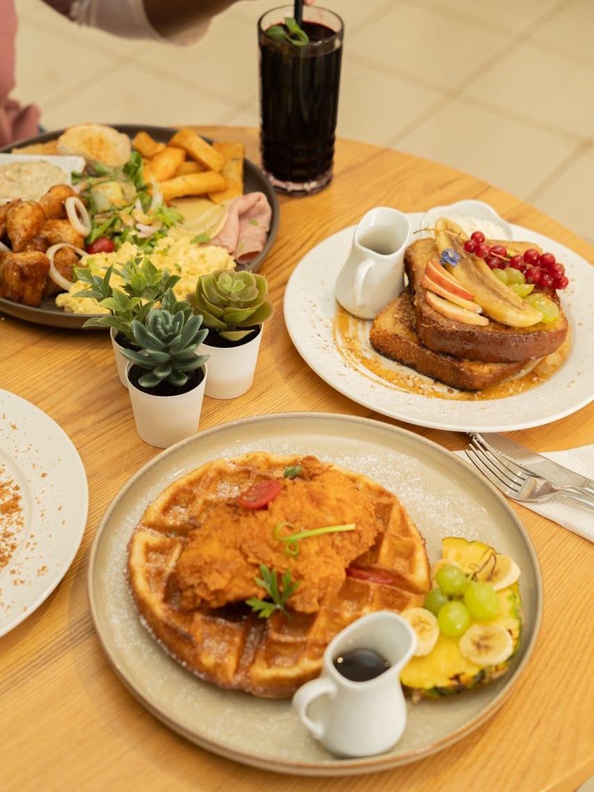 A brunch spread at JKO Brunch with chicken and waffles, toast, fries, and drinks